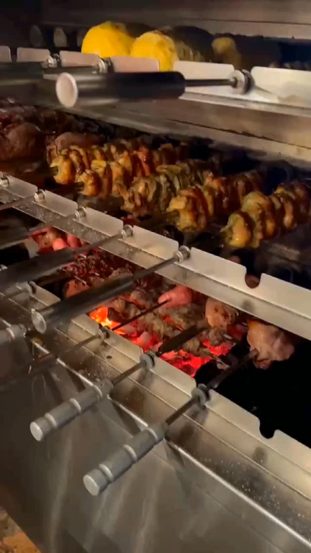 赤く燃える炭の上で焼ける鶏肉、ソーセージ、パイナップルの串。